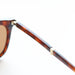 Close-up of a tortoiseshell folding sunglasses frame with a gold accent on a white background