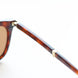 Close-up of a tortoiseshell folding sunglasses frame with a gold accent on a white background
