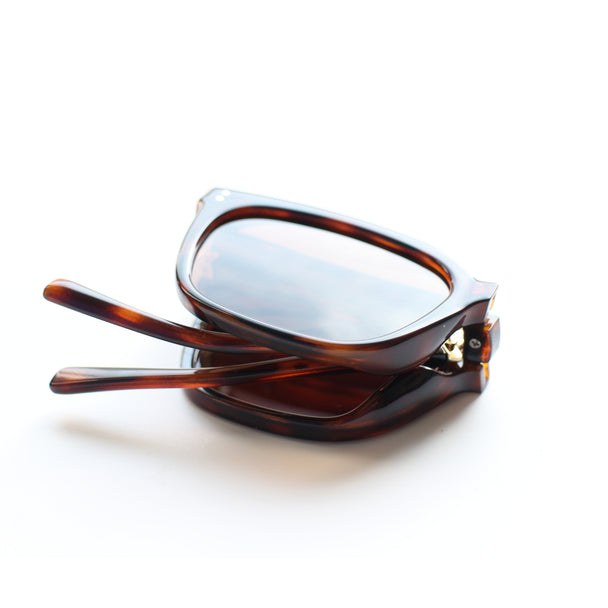 Sunglasses with tortoiseshell frame and reflective lenses on a white background